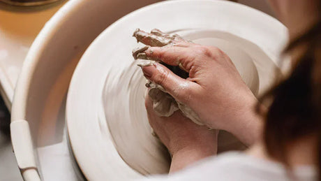 Mains façonnant de la terre dans l'atelier Elephantom